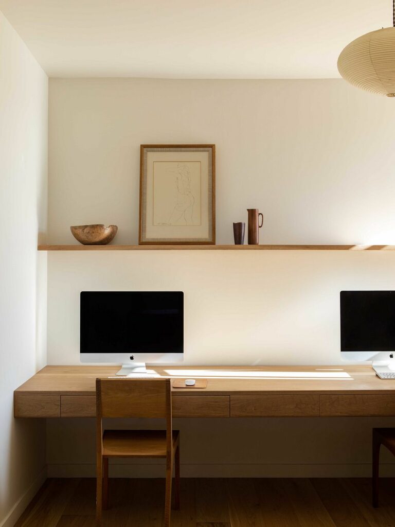 Een modern thuiskantoor met een lang bureau tegen de muur