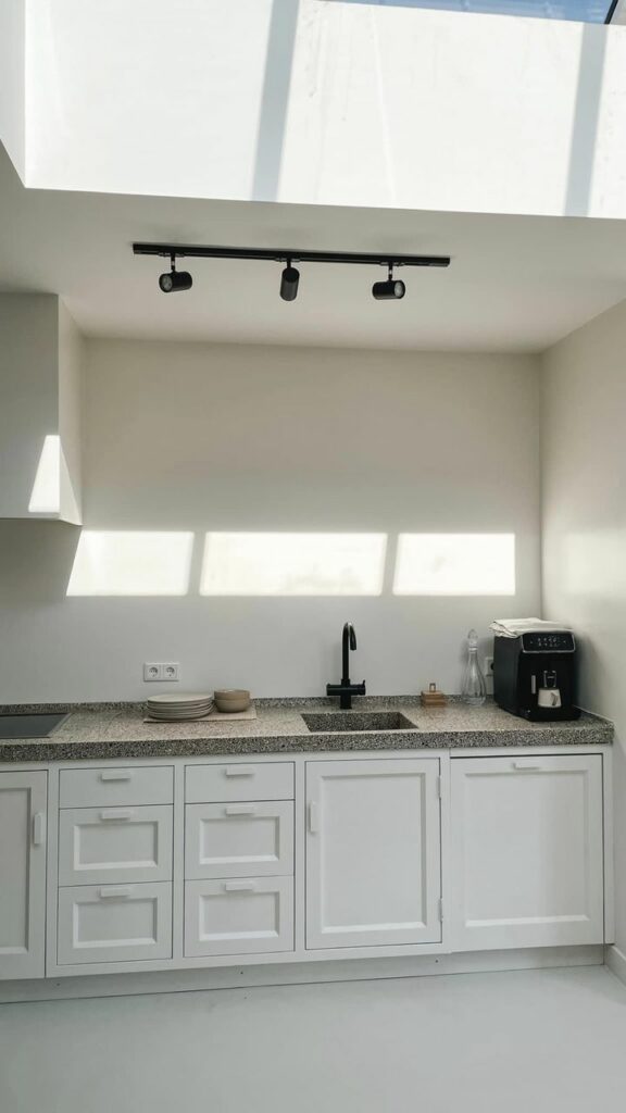 Een witte keuken met natuursteen keukenblad en zwarte kraan