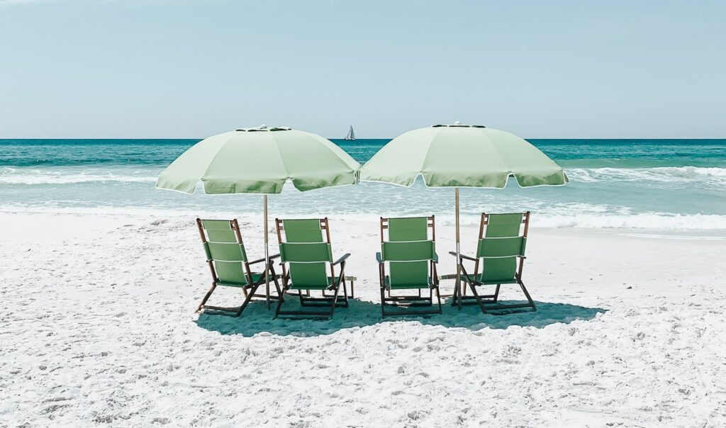 een strand met vier groene strandstoelen op een rijtje
