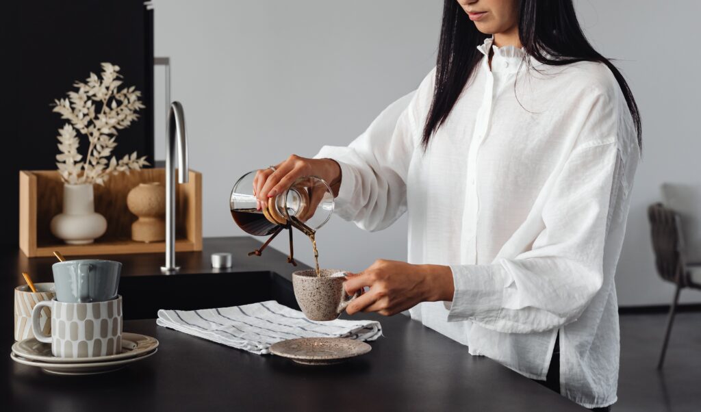 een vrouw in witte blouse maakt koffie in een keuken